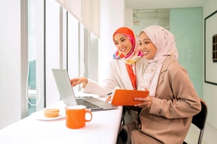 Two women in an office looking at a laptop