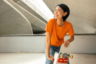 Young lady with a skateboard under a bridge